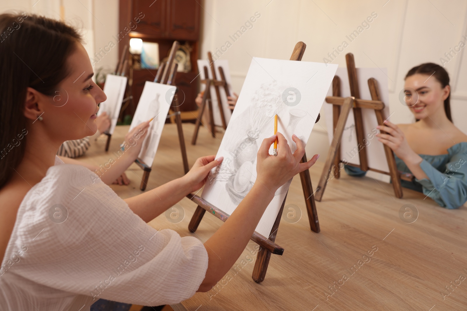 Photo of Group of women learning to draw at wooden table in class