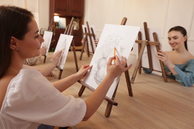 Photo of Group of women learning to draw at wooden table in class