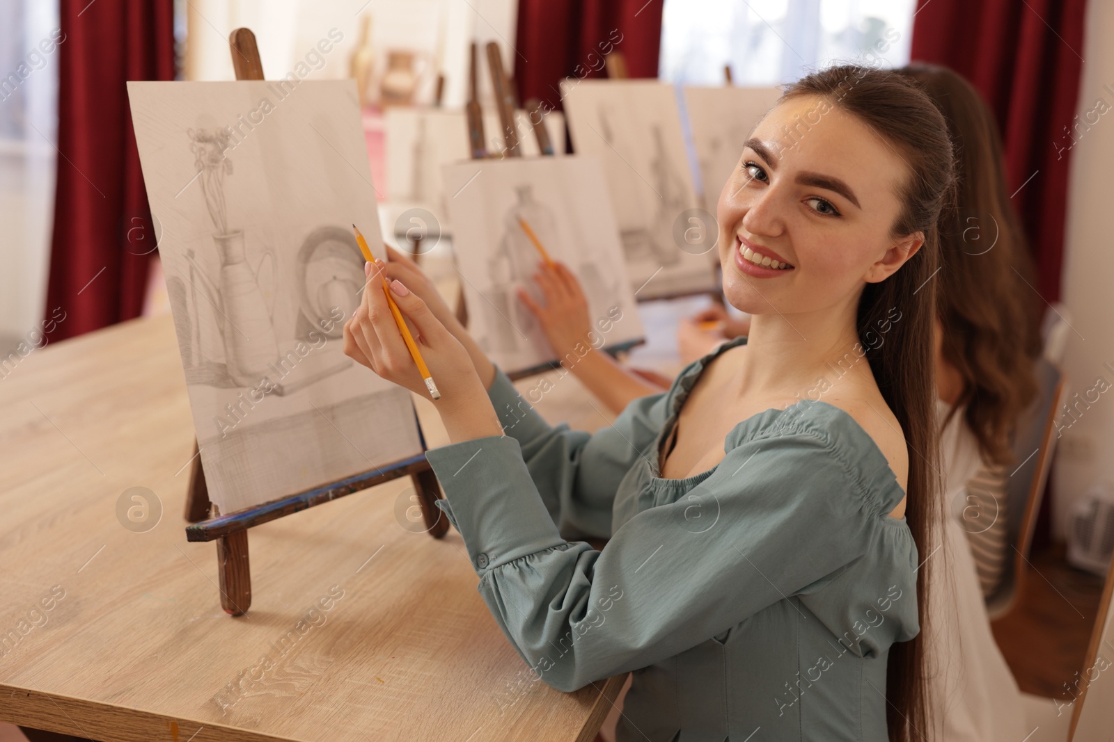 Photo of Group of women with easels learning to draw pictures at wooden table indoors