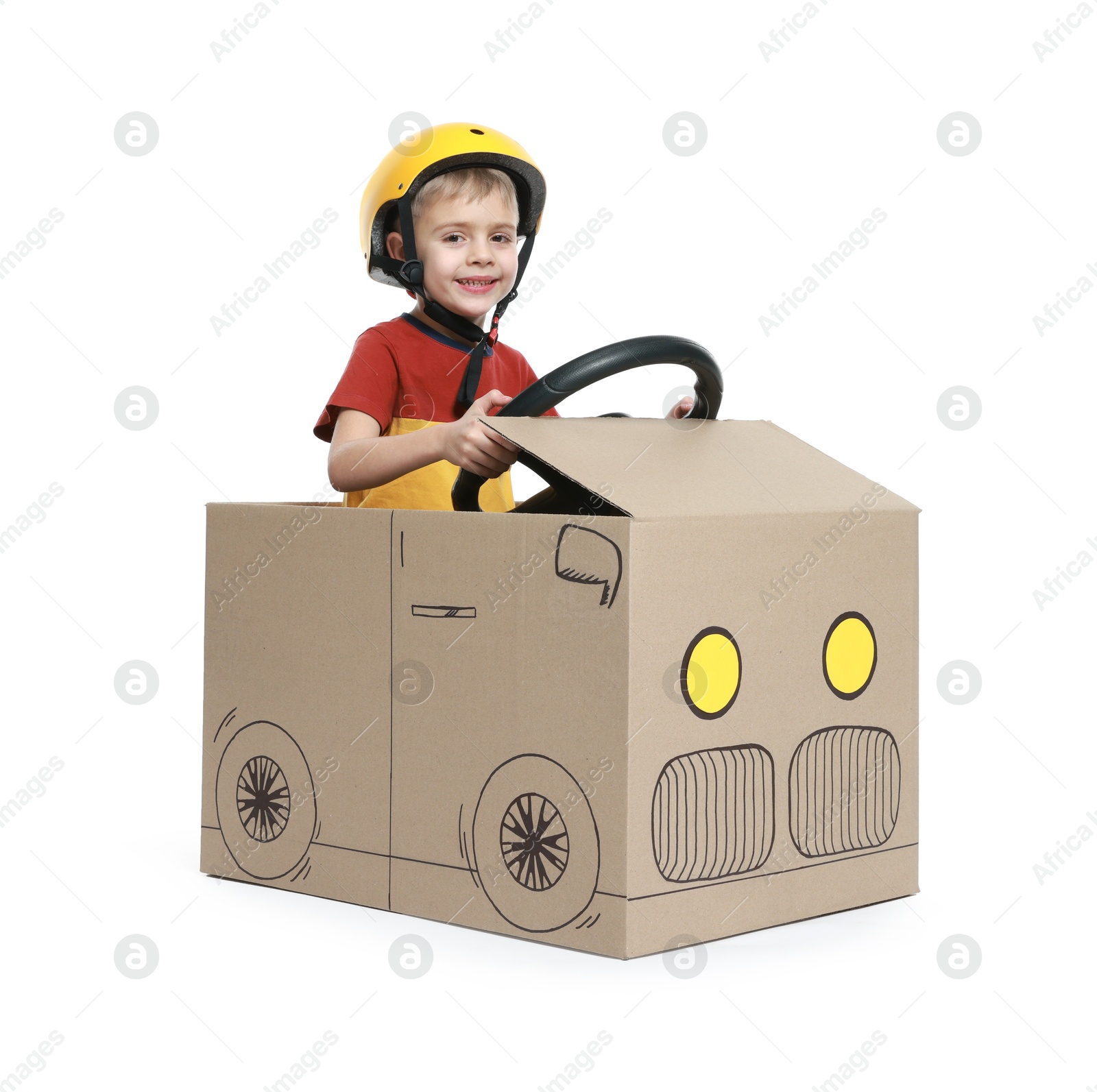 Photo of Little boy driving car made of cardboard on white background