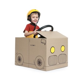 Photo of Little boy driving car made of cardboard on white background