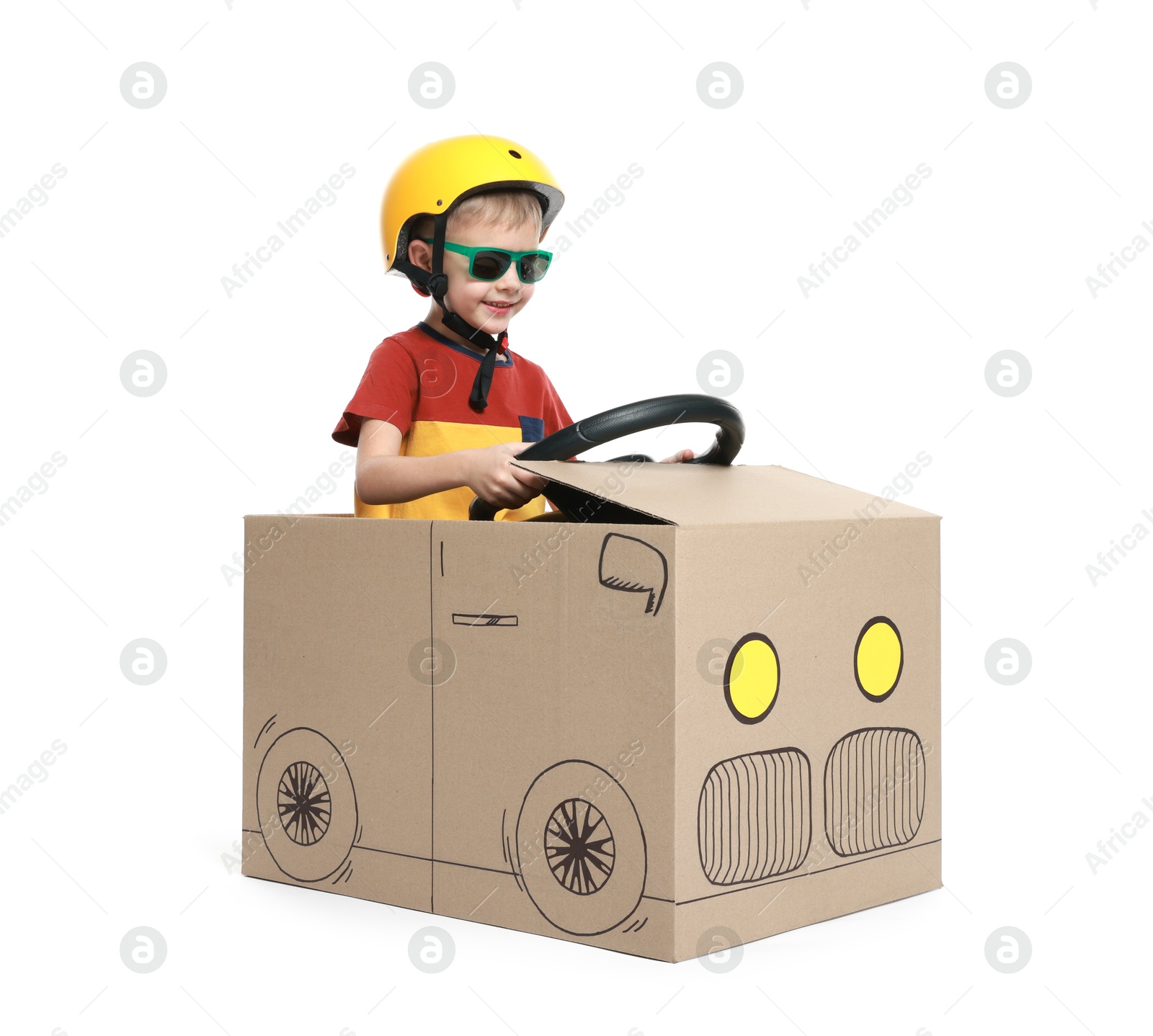 Photo of Little boy driving car made of cardboard on white background