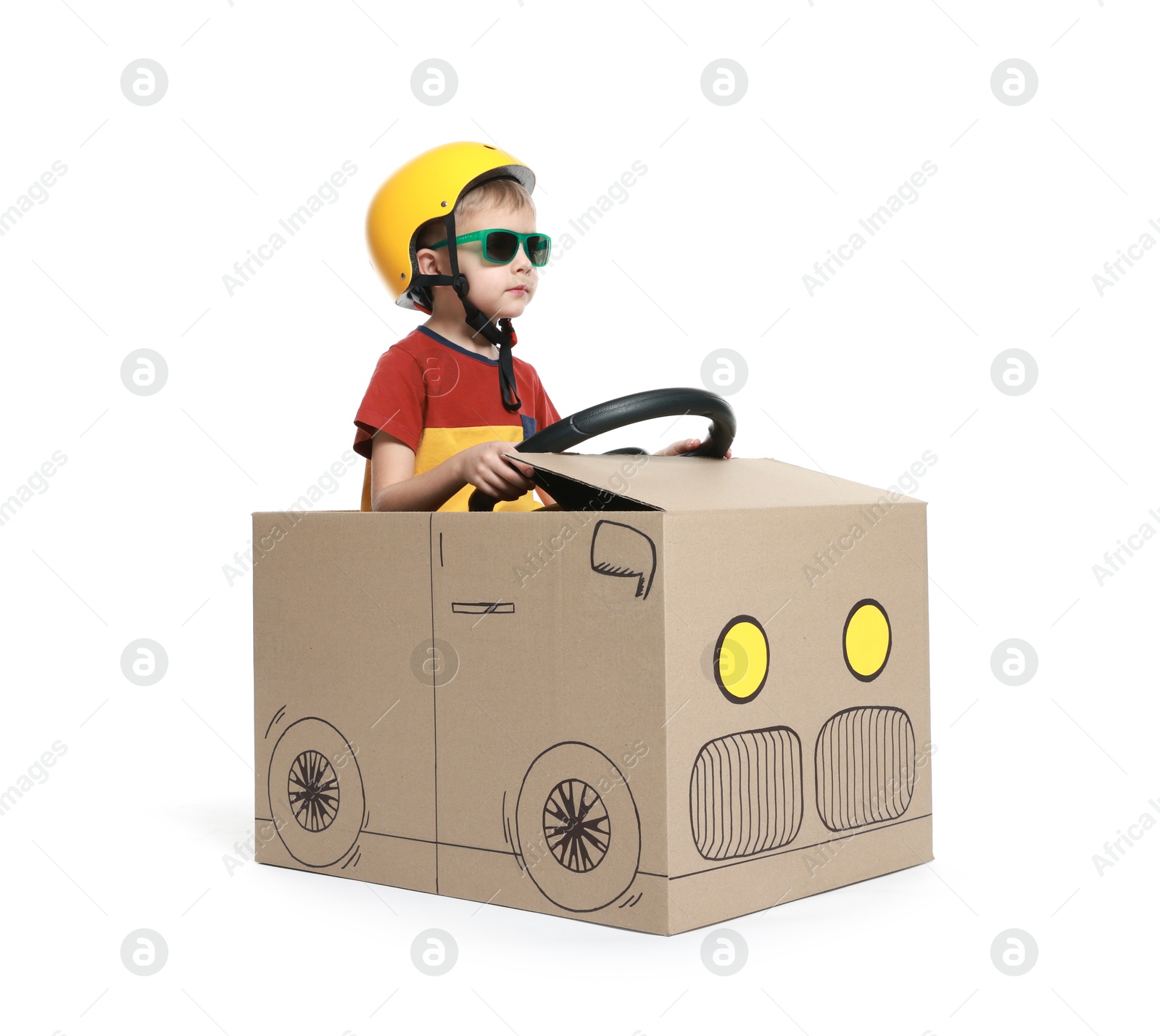 Photo of Little boy driving car made of cardboard on white background