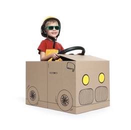 Little boy driving car made of cardboard on white background