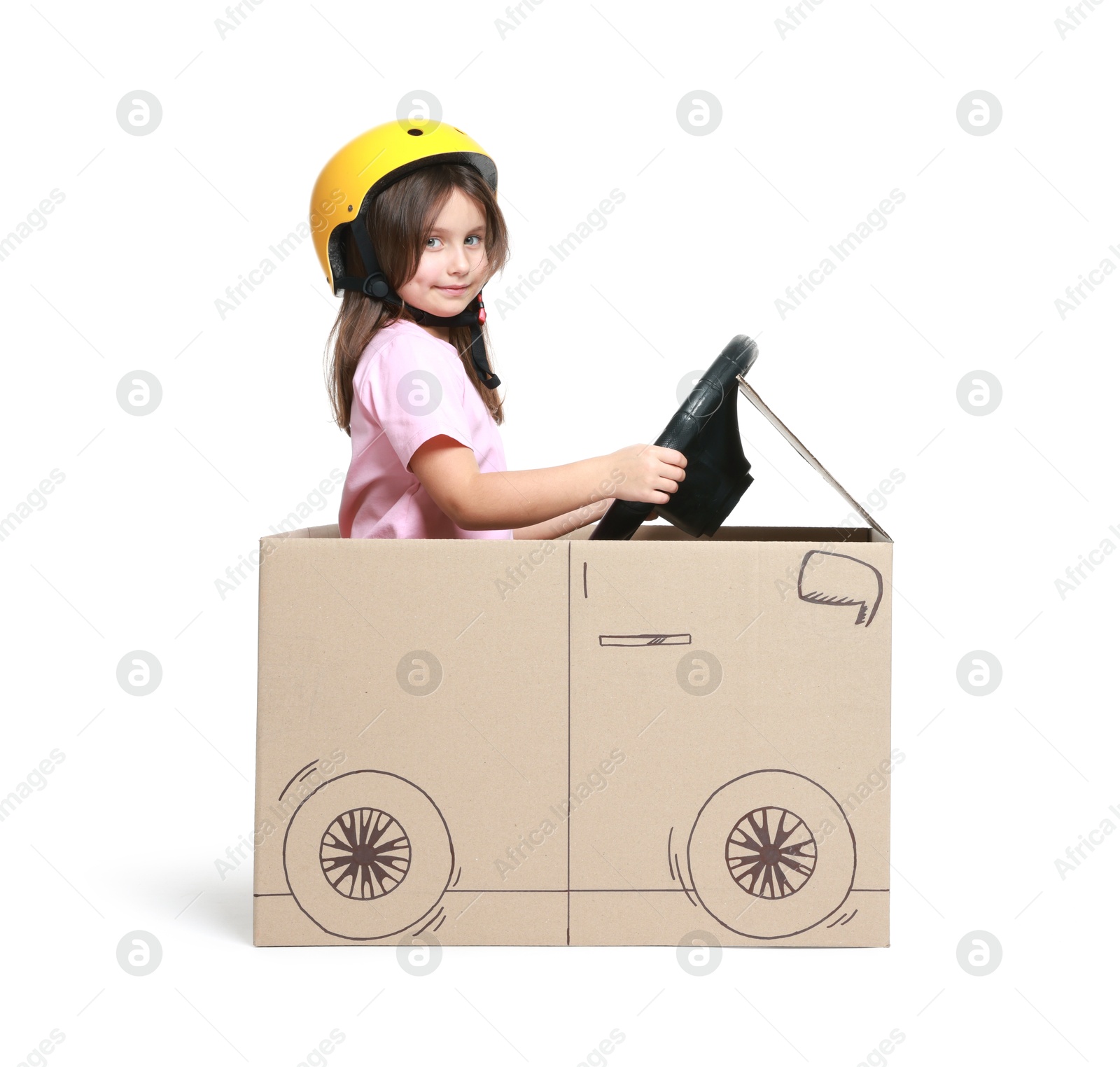 Photo of Little girl driving car made with cardboard on white background