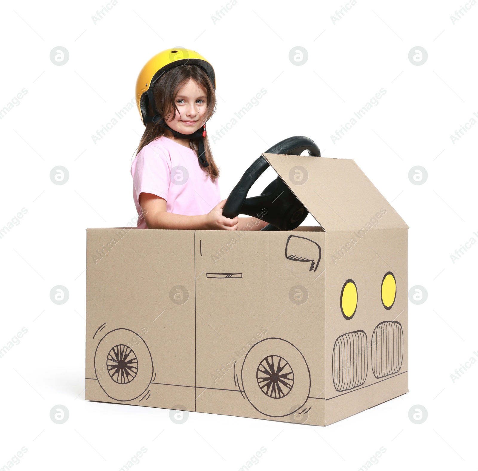 Photo of Little girl driving car made with cardboard on white background