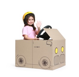 Photo of Little girl waving while driving car made with cardboard on white background