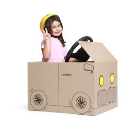 Photo of Little girl showing V-sign while driving car made with cardboard on white background