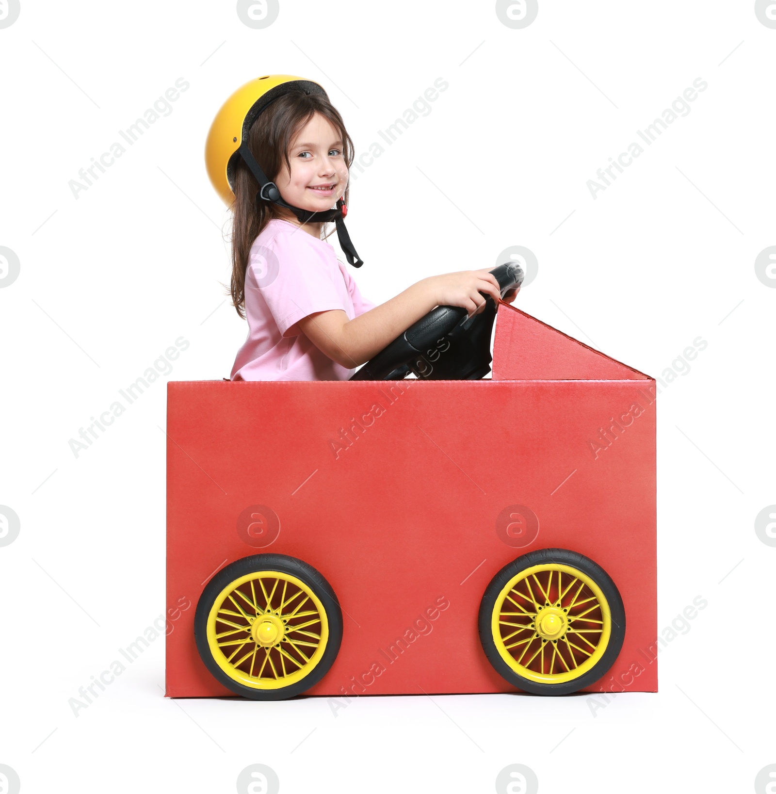 Photo of Little girl driving car made with cardboard on white background