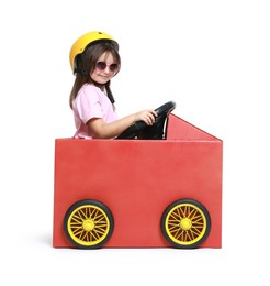 Photo of Little girl driving car made with cardboard on white background