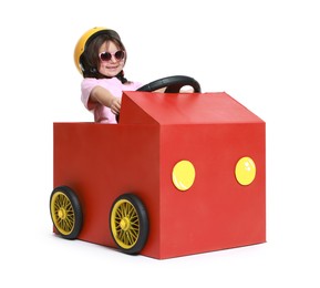 Photo of Little girl driving car made with cardboard on white background