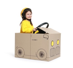 Photo of Little girl driving car made with cardboard on white background