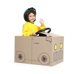 Photo of Little girl waving while driving car made with cardboard on white background