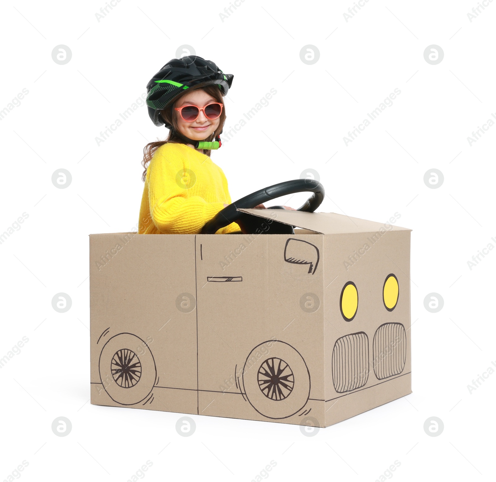 Photo of Little girl driving car made with cardboard on white background