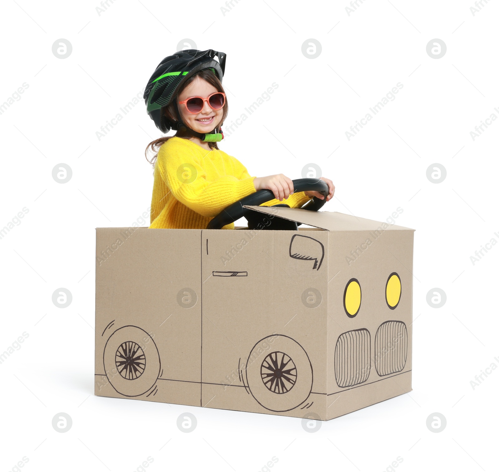 Photo of Little girl driving car made with cardboard on white background