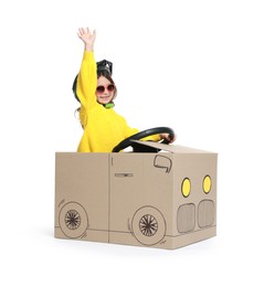 Photo of Little girl waving while driving car made with cardboard on white background