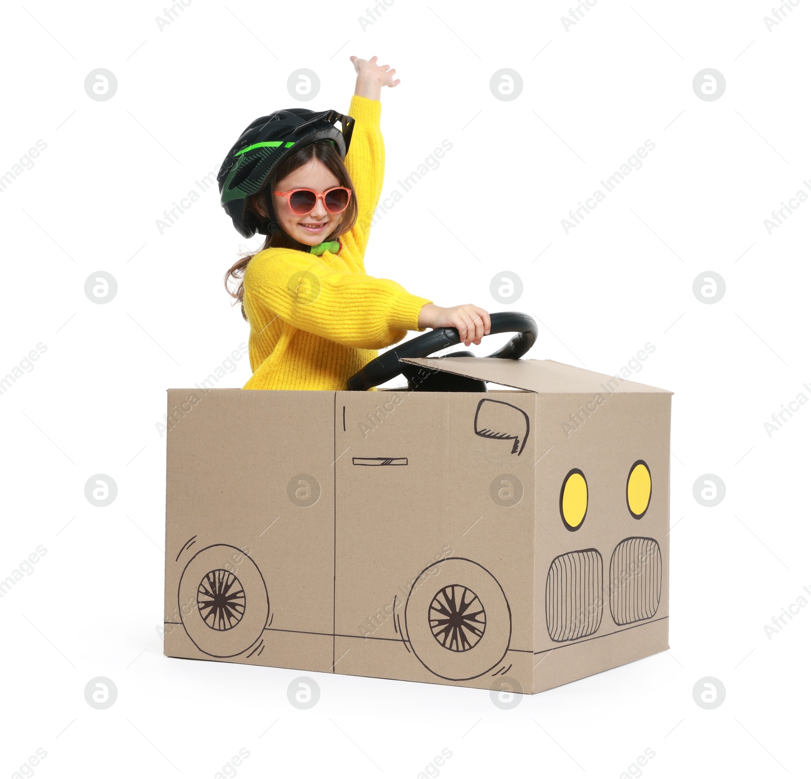 Photo of Little girl waving while driving car made with cardboard on white background