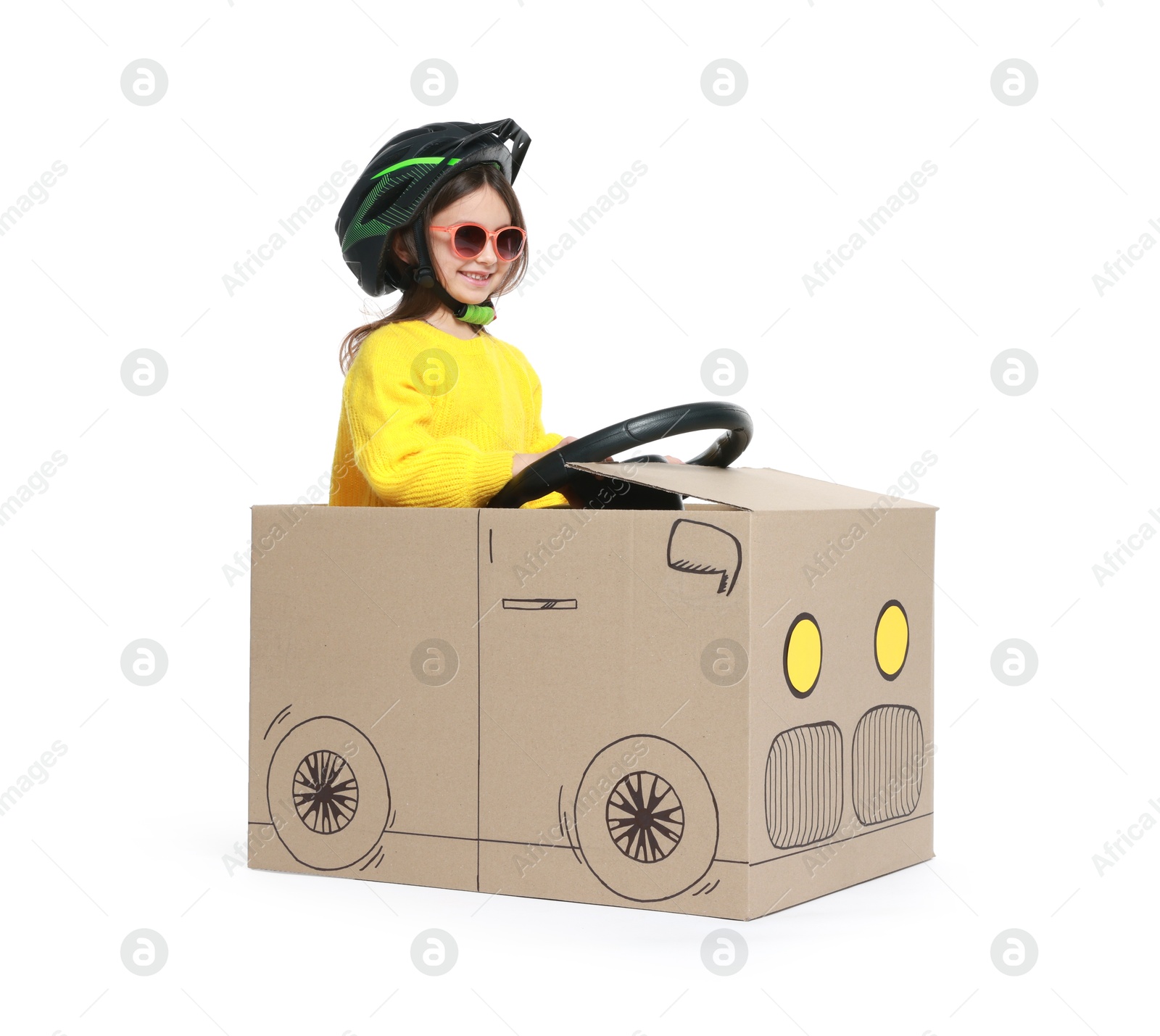 Photo of Little girl driving car made with cardboard on white background