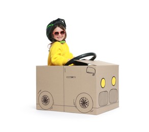 Photo of Little girl driving car made with cardboard on white background