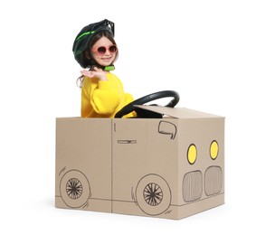 Photo of Little girl driving car made with cardboard on white background