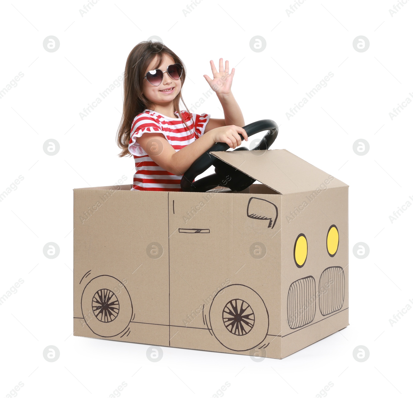 Photo of Little girl waving while driving car made with cardboard on white background