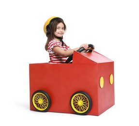 Photo of Little girl driving car made with cardboard on white background