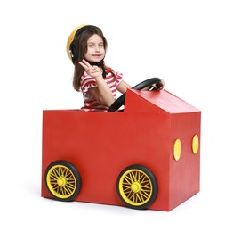 Photo of Little girl showing V-sign while driving car made with cardboard on white background