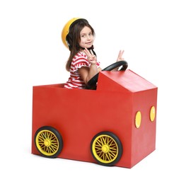 Photo of Little girl showing V-sign while driving car made with cardboard on white background