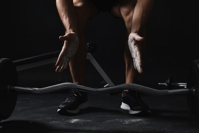 Photo of Man clapping hands with talcum powder before training with barbell in gym, closeup