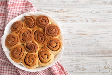 Freshly baked cinnamon rolls on light wooden table, top view. Space for text