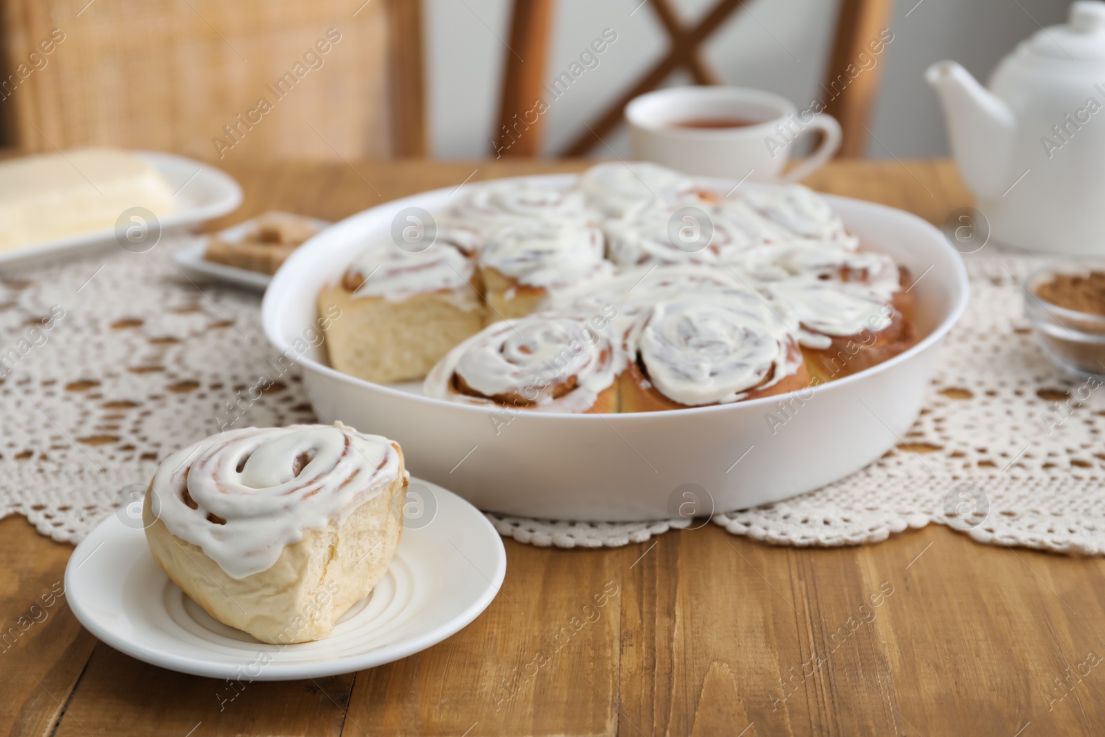 Photo of Delicious frosted cinnamon rolls on wooden table indoors, closeup