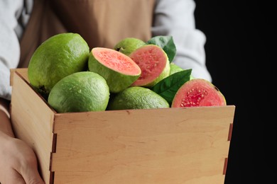 Photo of Woman with fresh guava fruits on black background, closeup