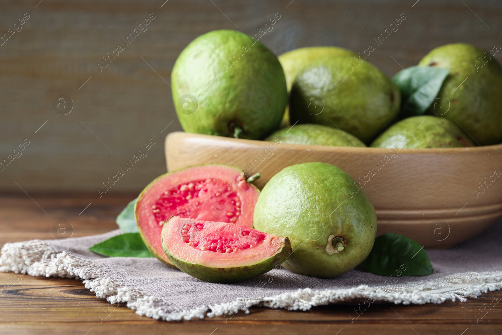 Photo of Fresh cut and whole guava fruits on wooden table, closeup