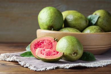 Photo of Fresh cut and whole guava fruits on wooden table, closeup