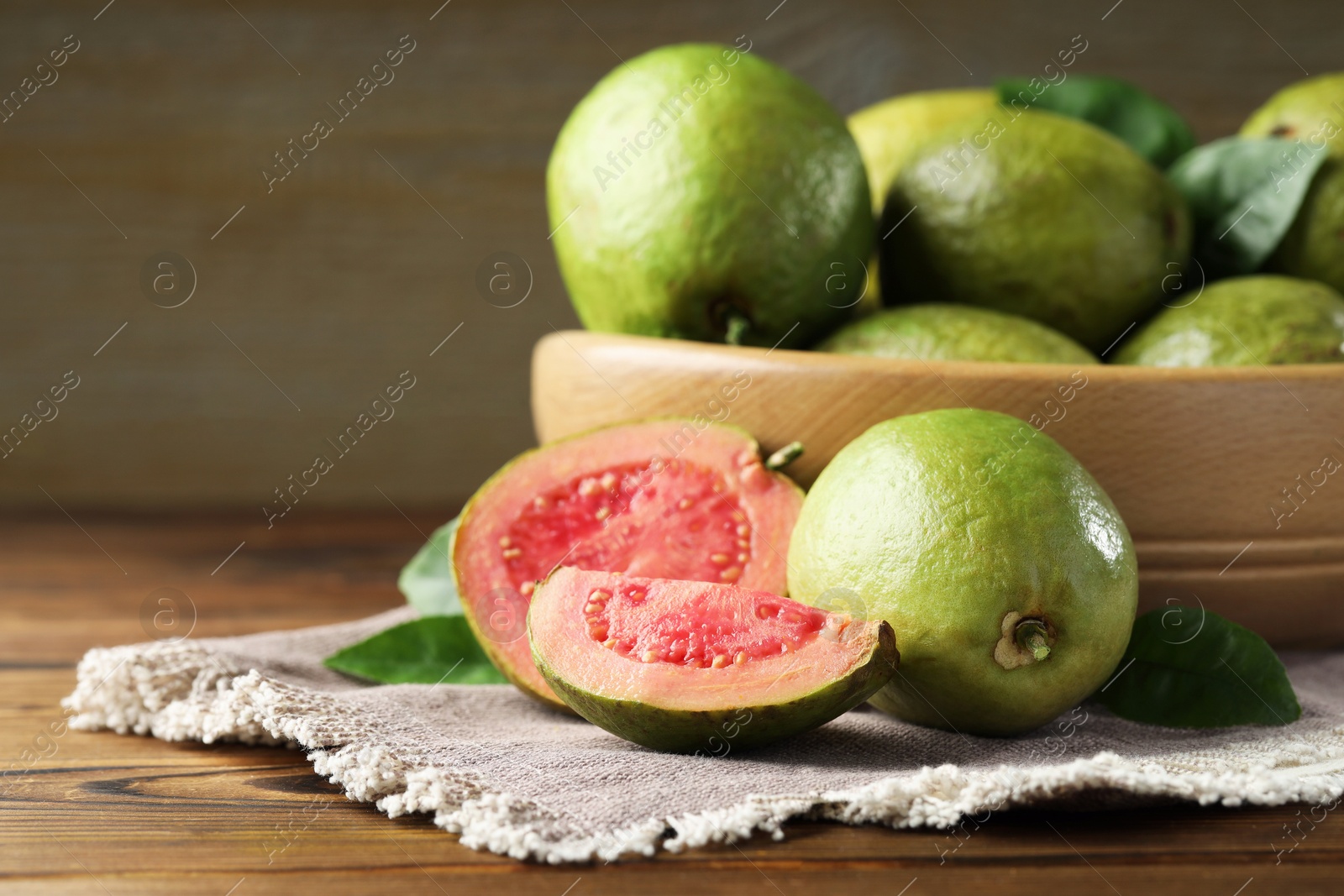 Photo of Fresh cut and whole guava fruits on wooden table, closeup