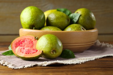 Photo of Fresh cut and whole guava fruits on wooden table, closeup