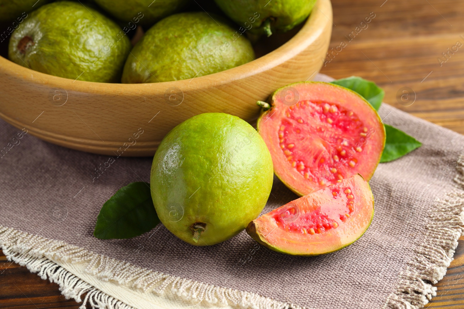 Photo of Fresh cut and whole guava fruits on wooden table