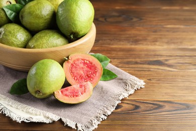 Fresh cut and whole guava fruits on wooden table. Space for text