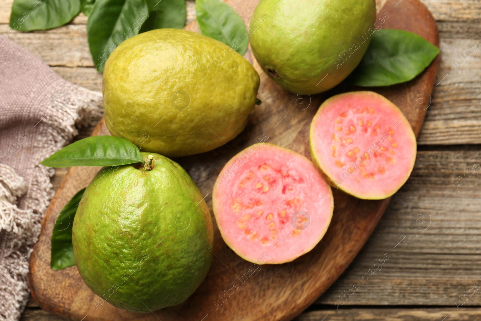 Photo of Fresh whole and cut guava fruits on wooden table, above view