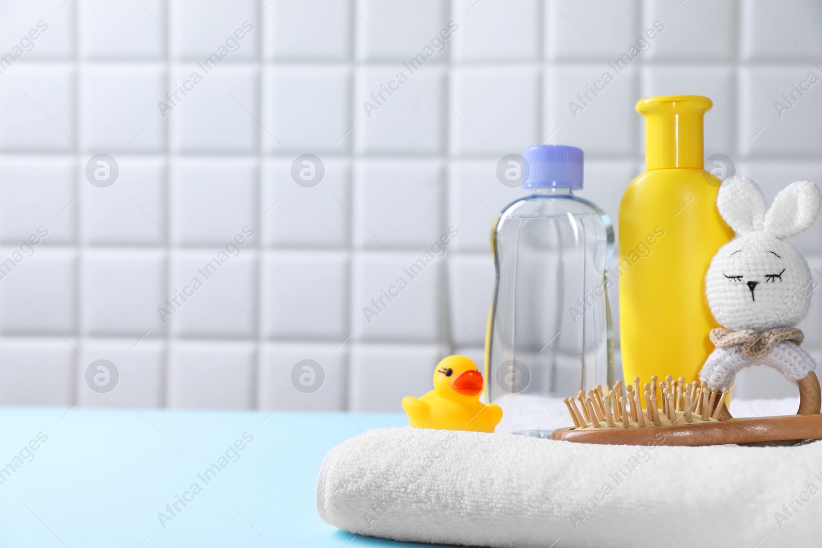 Photo of Baby oil and bath accessories on light table. Space for text