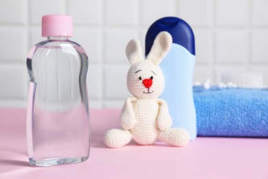 Photo of Baby oil and bath accessories on pink table, selective focus