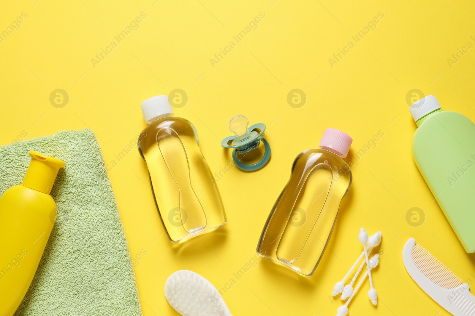 Photo of Baby oil and bath accessories on yellow background, flat lay