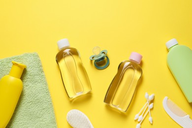 Photo of Baby oil and bath accessories on yellow background, flat lay