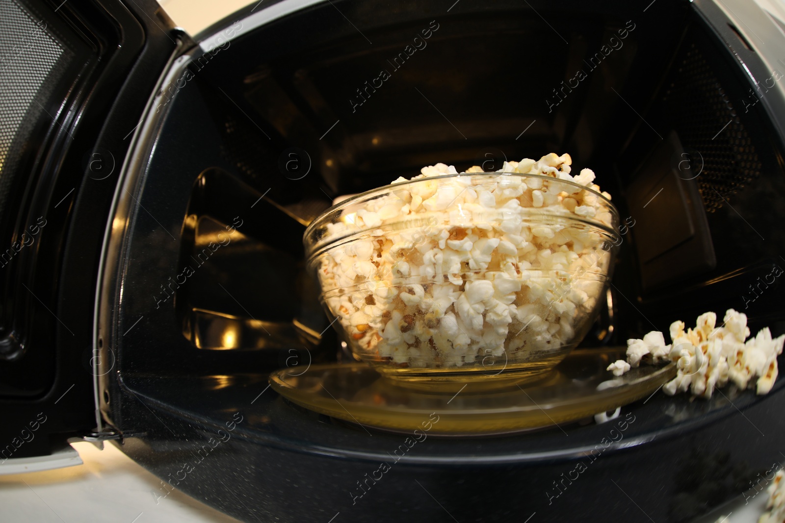 Photo of Bowl of tasty popcorn in microwave oven, closeup. Fisheye lens effect