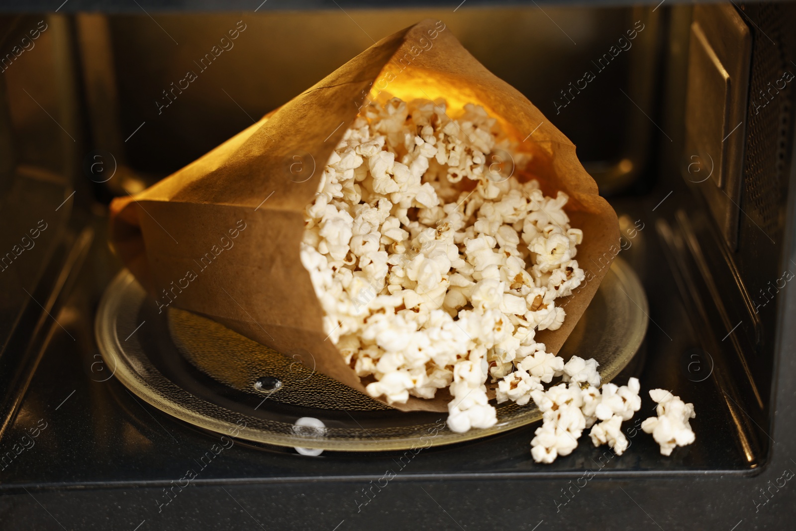 Photo of Bag of tasty popcorn in microwave oven, closeup