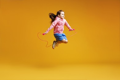 Photo of Cute little girl with jump rope on yellow background