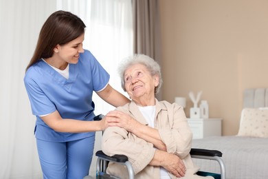 Photo of Healthcare worker with elderly woman in wheelchair indoors