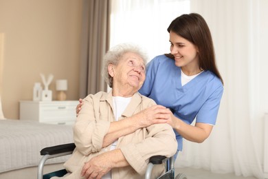 Photo of Healthcare worker with elderly woman in wheelchair indoors