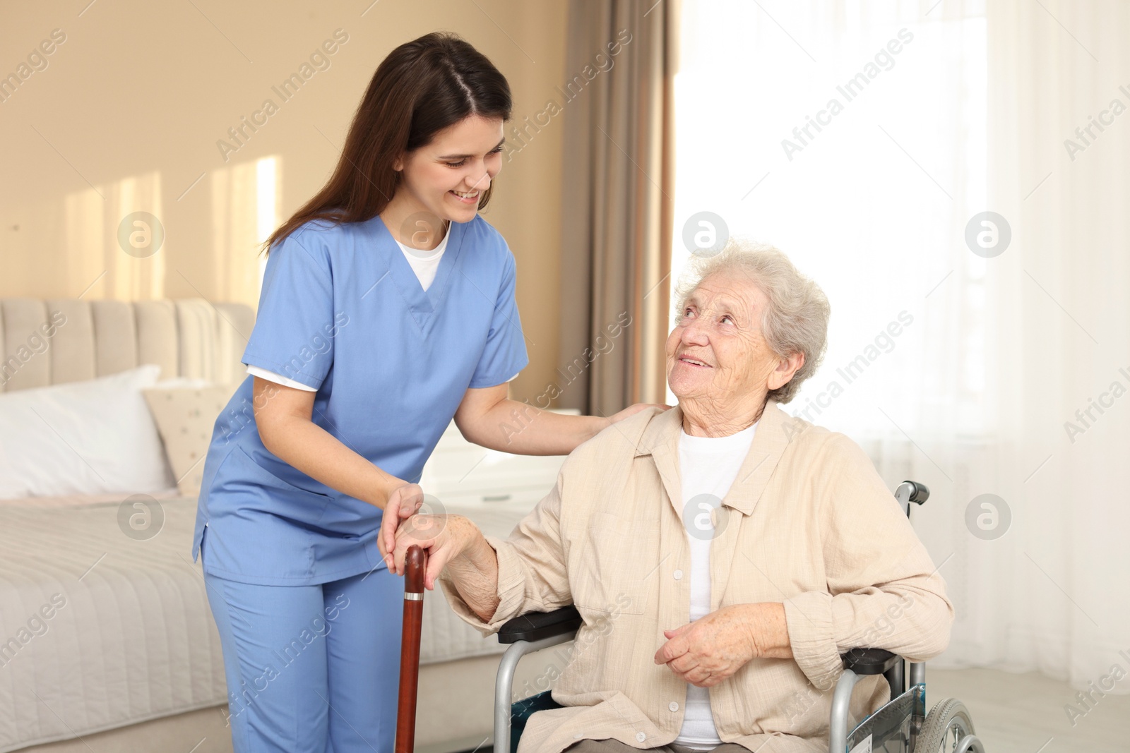 Photo of Healthcare worker with elderly woman in wheelchair indoors