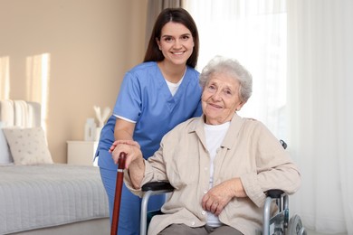 Healthcare worker with elderly woman in wheelchair indoors